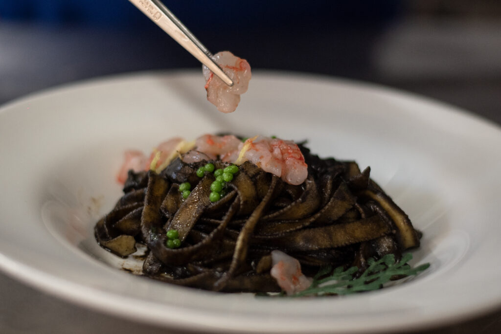 Foto con tagliatella al nero di seppia e tartare di gambero rosso
